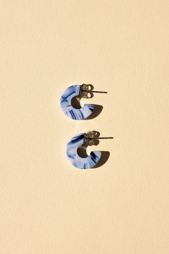 NAT & NOOR Ethically Made Sustainable Jewelry - Nora Mini Huggie Size Hoop Earrings in Ocean Blue Acetate Tortoise on Flat Surface