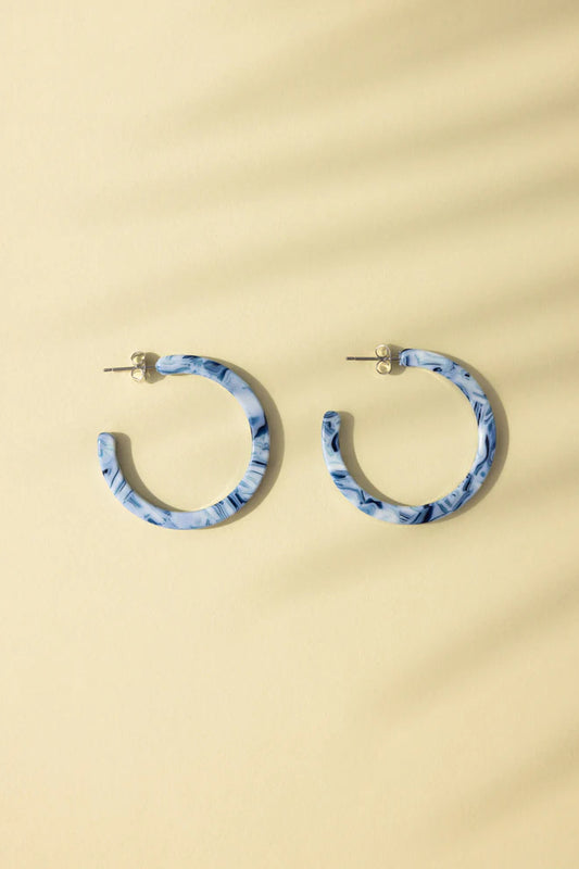 NAT & NOOR Ethically Made Sustainable Jewelry - Nora Mid Size Hoop in Blue Ocean Tortoise on Flat Surface