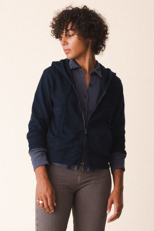 Image of model wearing Prairie Underground Simple Life Hoodie in Midnight Navy Blue. Simple Life is a slightly cropped zip front hoodie sweatshirt made from an organic cotton fleece. Designed and produced in Seattle, Washington.