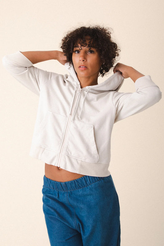 Image of model wearing Prairie Underground Simple Life Hoodie in Oyster White. Simple Life is a slightly cropped zip front hoodie sweatshirt made from an organic cotton fleece. Designed and produced in Seattle, Washington.