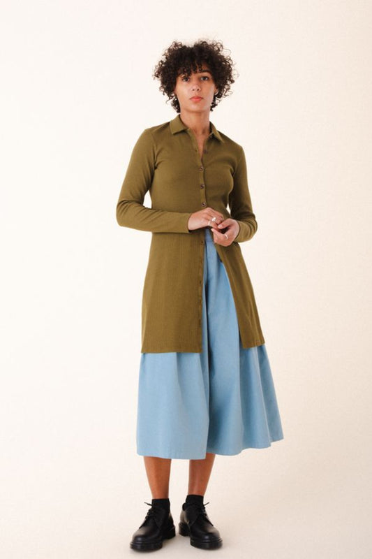 Image of model wearing Cavalos Shirt Dress in Herb Green Rib. Cavalos is a fitted shirt dess with a classic collar that hits mid-thigh made from organic cotton Ribbed fabric.