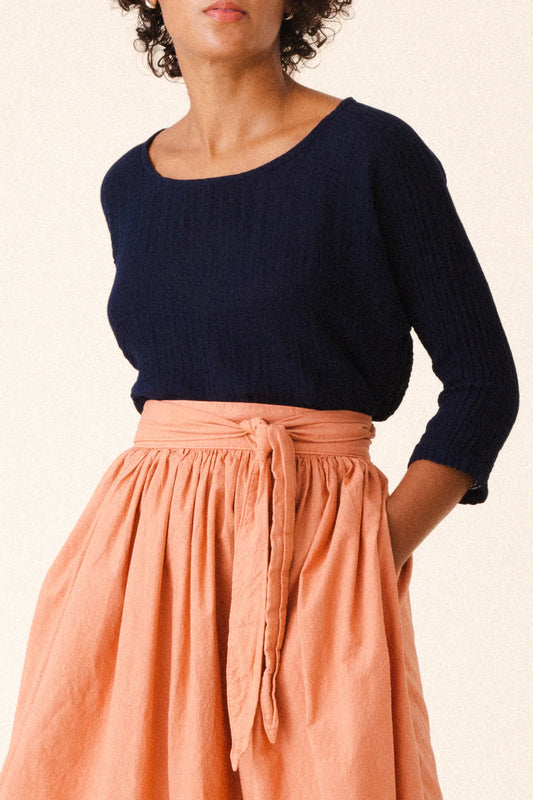 Image of model wearing Prairie Underground Interval Wrap Skirt in Cedar Chest. Interval Skirt is a true wrap skirt that hits below the knee with a sash tie, made in Seattle, Washington from a Cedar Pink organic cotton muslin.