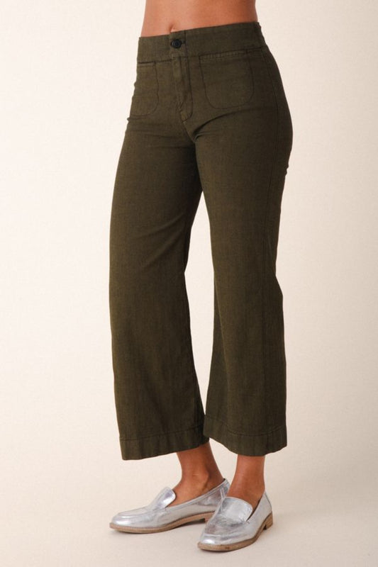 Image of model wearing Prairie Underground Document Jean in Herb Green. This zip fly Jean has a cropped inseam with a kick flare leg opening. Designed and made in USA.