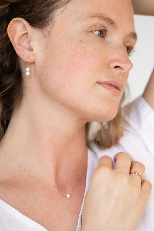 Image of Sheena Marshall Jewelry handmade Pearl Grit Necklace on model - single pearl strung on 14k goldfill chain. Simple, luxurious jewelry handmade in Denver, Colorado.