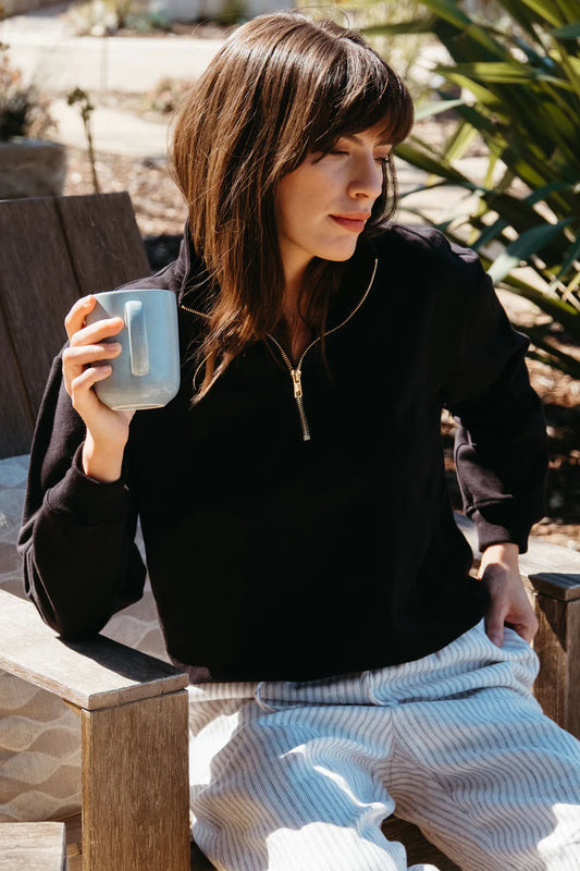 Image of model wearing Whimsy + Row Diana Half Zip Pullover in Black. Made in USA from organic cotton fleece.
