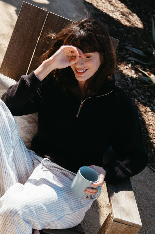 Image of model wearing Whimsy + Row Diana Half Zip Pullover in Black. Made in USA from organic cotton fleece.