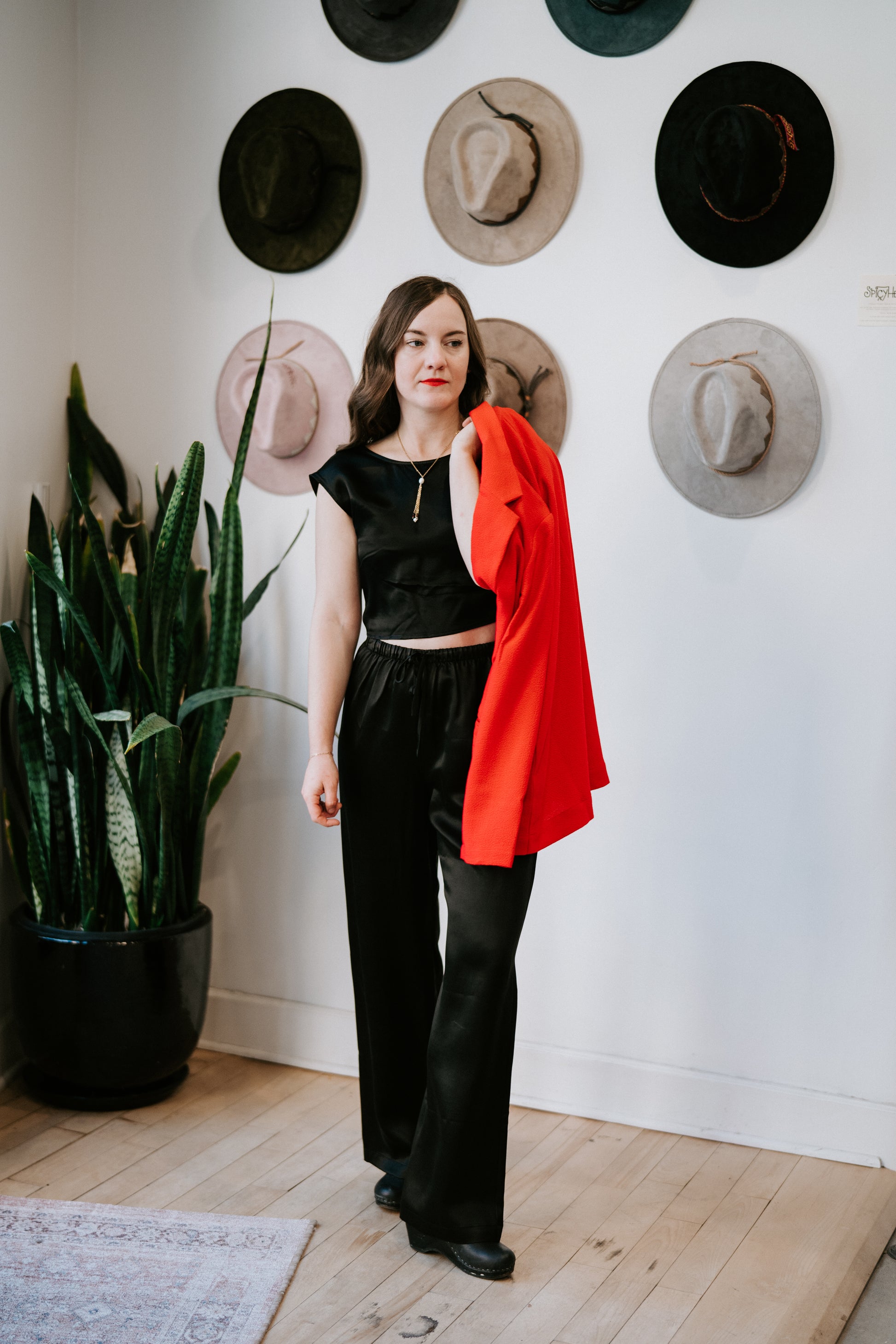 Image of model in Whimsy and Row Black Valentine Vegan Silk Tie Top and Whimsy and Row Black Raffa Vegan Silk Pull-On Pant Holding Red Blazer - Ethically Made Holiday Fashion - Made in Los Angeles Women's Apparel