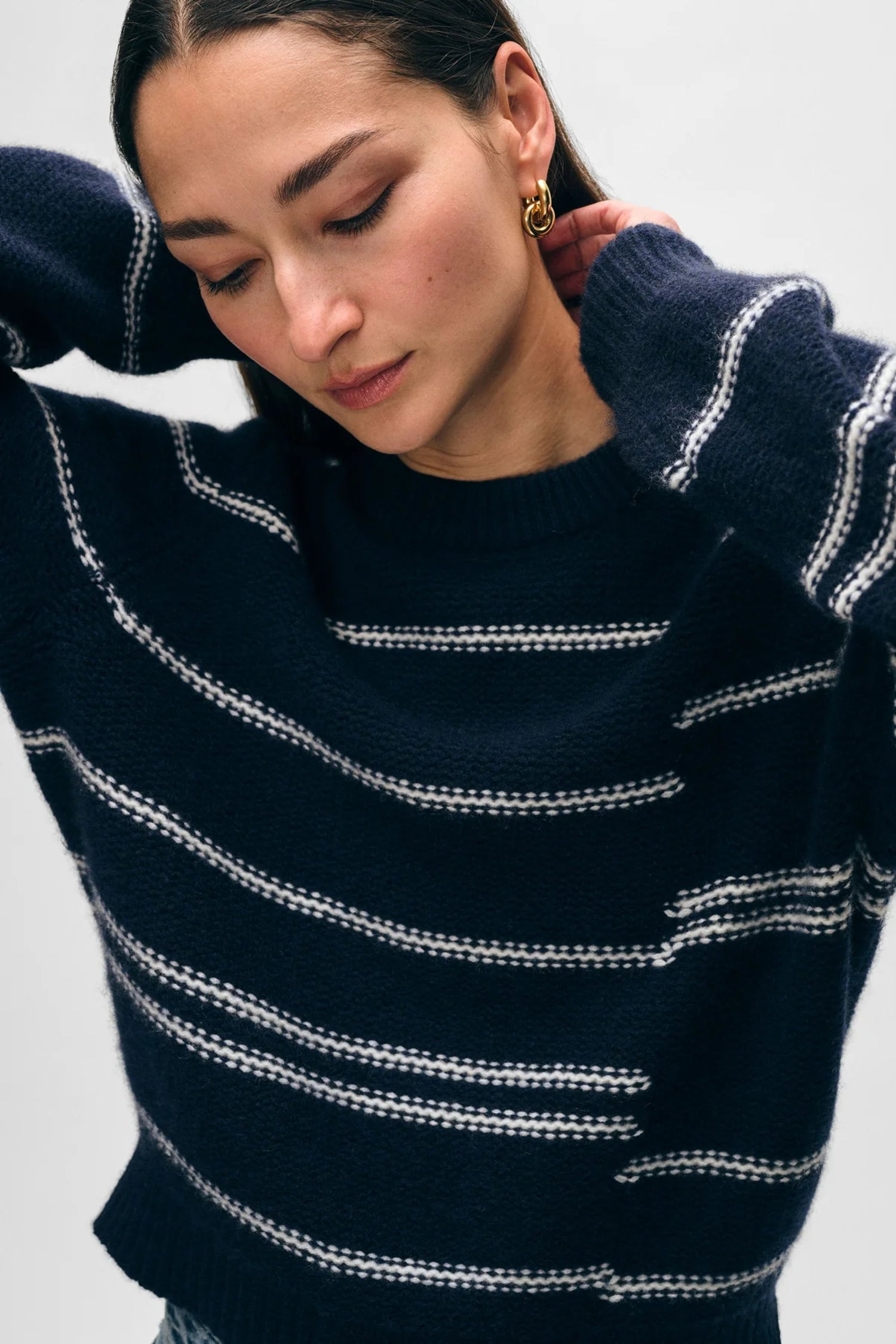 Image of model wearing White + Warren Responsible Lofty Cashmere Broken Stripe Sweater. This is a classic crewneck sweater with a navy backdrop and slightly abstract soft white stripes. 