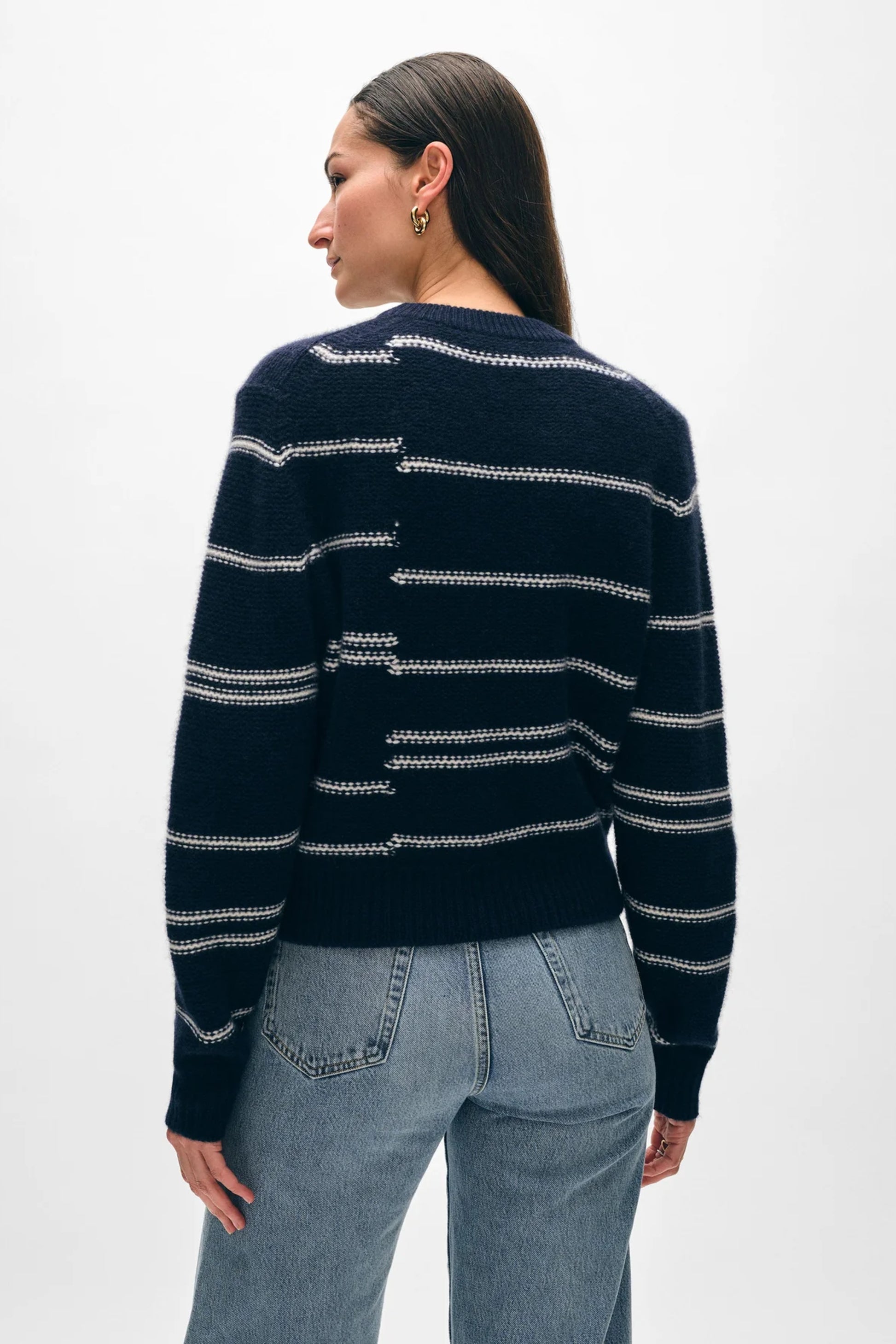 Image of model wearing White + Warren Responsible Lofty Cashmere Broken Stripe Sweater. This is a classic crewneck sweater with a navy backdrop and slightly abstract soft white stripes. 