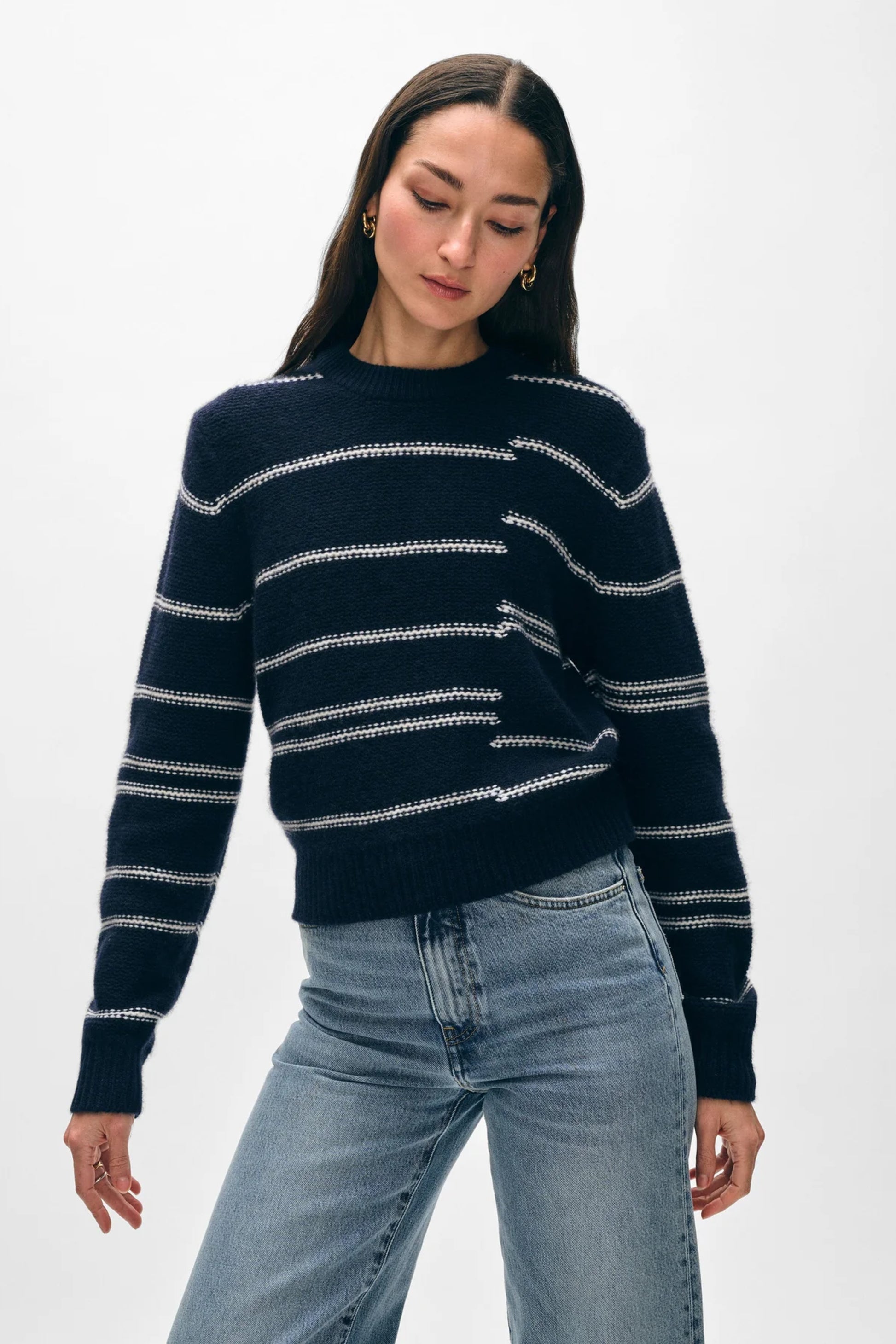 Image of model wearing White + Warren Responsible Lofty Cashmere Broken Stripe Sweater. This is a classic crewneck sweater with a navy backdrop and slightly abstract soft white stripes. 